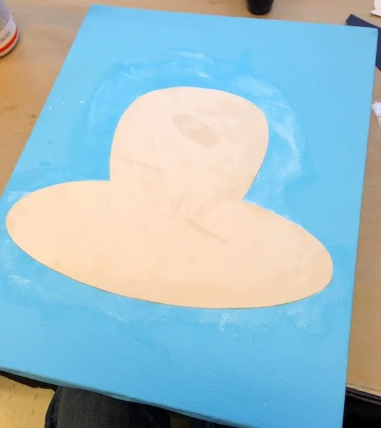 Cardstock head shape Mod Podged to a blue canvas