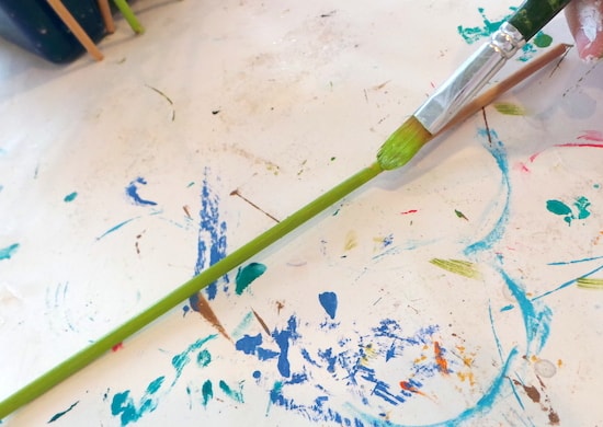 Painting a dowel rod with bright green paint