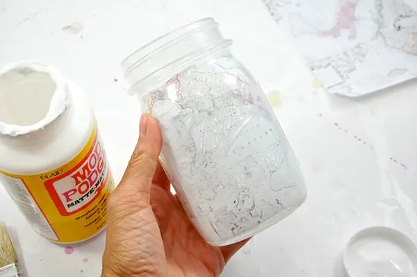 Hand holding a mason jar with a map inside