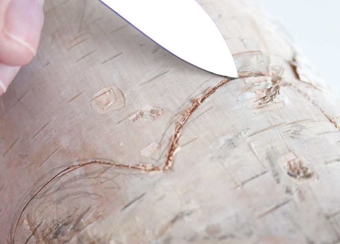 Using a knife to carve on the pencil lines on the birch pillar