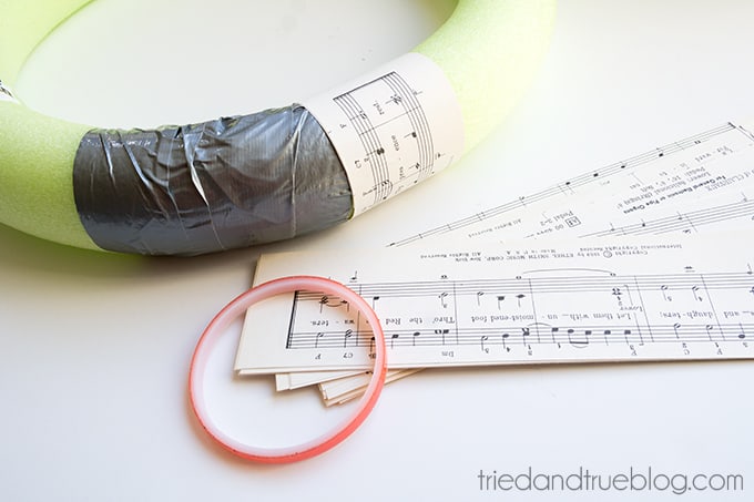 Pool noodle wreath form being covered with music sheets