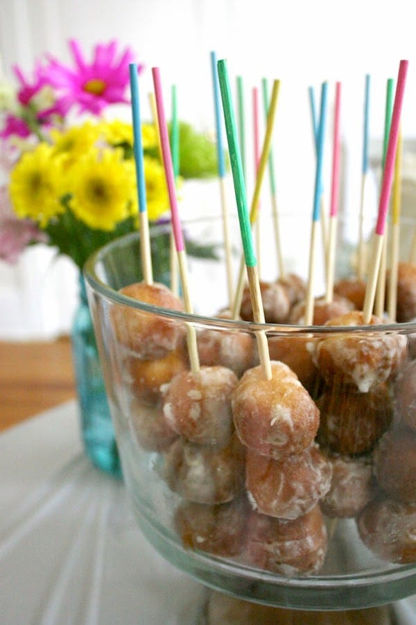 Painted wood skewers with donut holes in a glass dish