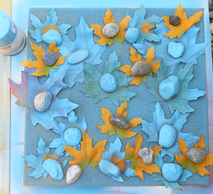 Spraying leaves and canvas with blue spray paint