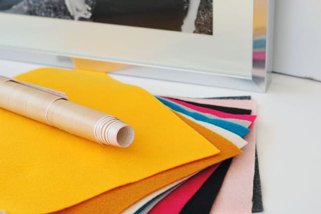 Stack of colorful felt with a woodgrain roll of contact paper on top