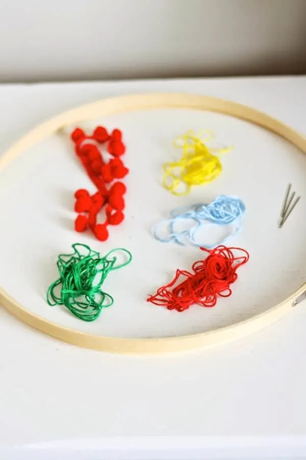 Embroidery hoop, thread in different colors, needles, and pom pom trims