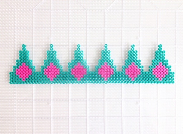 Perler beads on a pegboard forming a crown pattern