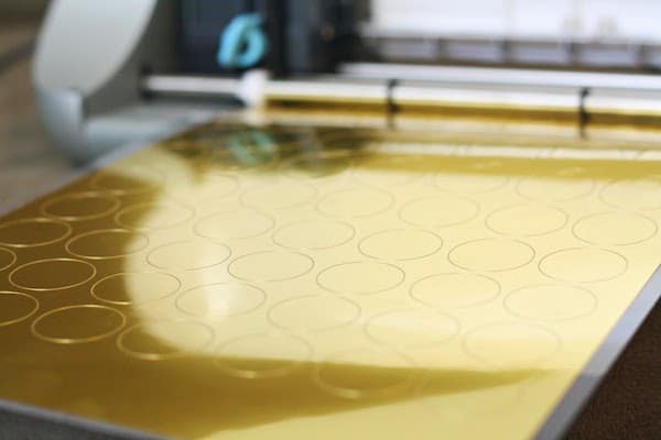 Silhouette machine cutting circles out of gold vinyl