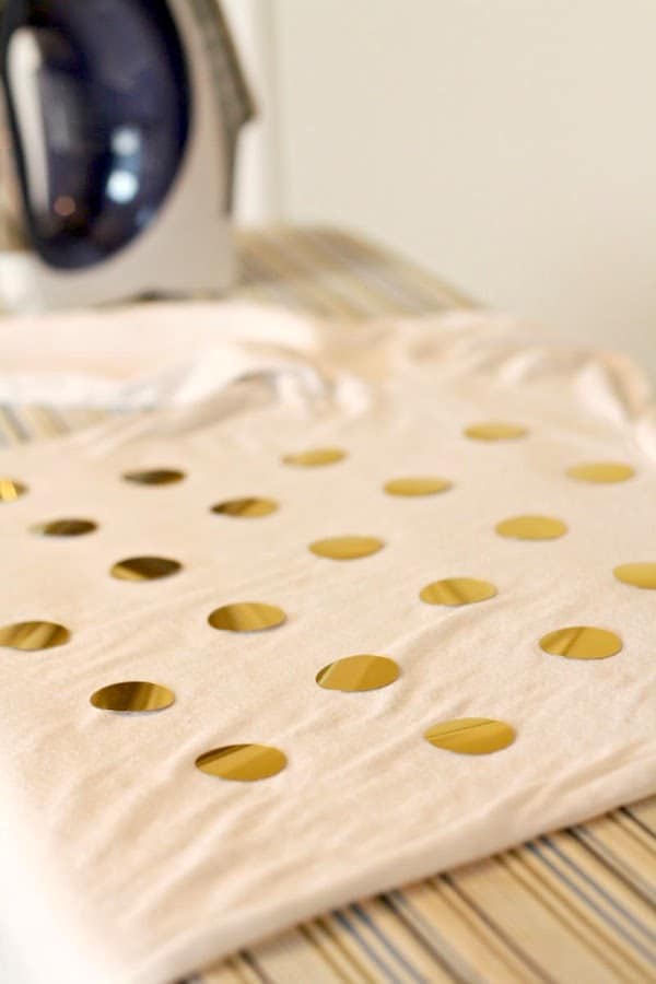 Gold circles laid out on a t-shirt on the ironing board