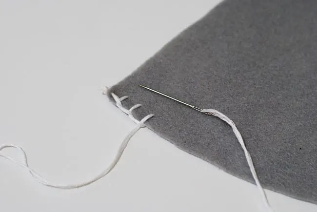 Blanket stitch at the end of a piece of felt with white embroidery floss and a needle
