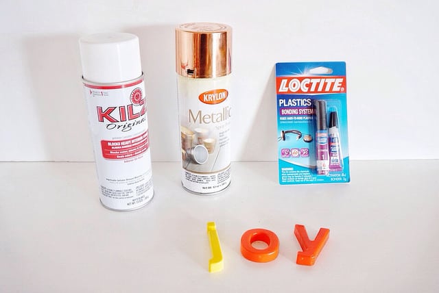 White spray primer, metallic spray paint, plastic super glue, and plastic letters spelling JOY