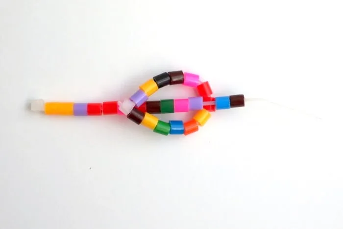 Loop of perler beads with another zip tie and perler beads pulled through the loop