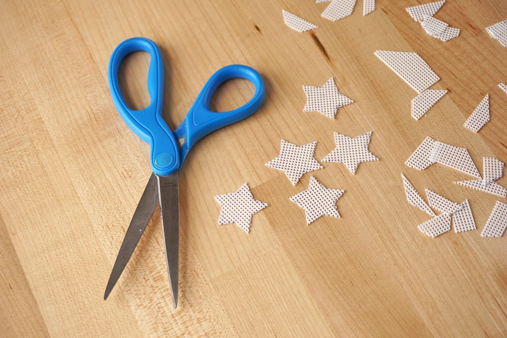 Stars cut out of plastic canvas with a pair of scissors laying next to them