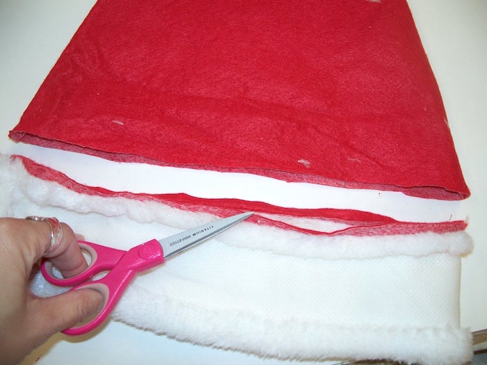 Trimming off the bottom of a Santa hat using scissors