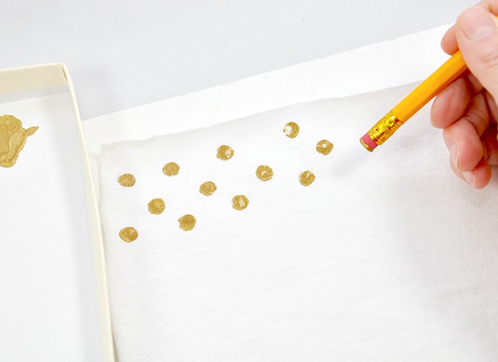Pressing gold paint down onto t-shirt material using a pencil eraser