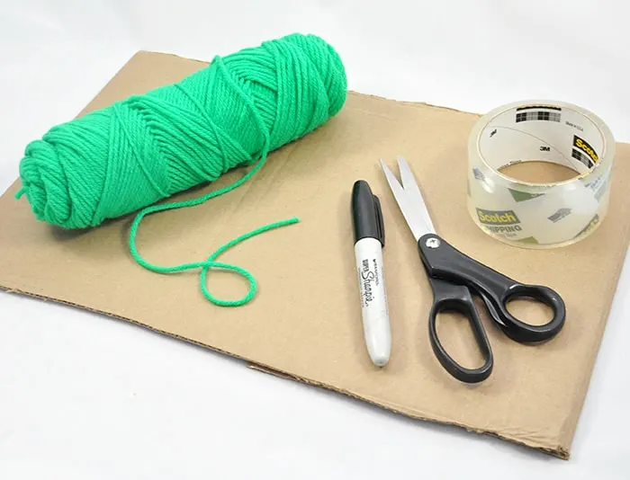 Piece of cardboard, skein of yarn, scissors, tape, and a Sharpie