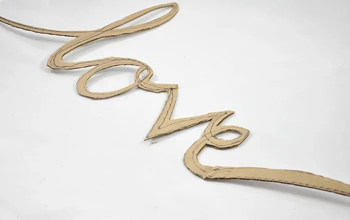 Love written in cursive and cut out of cardboard