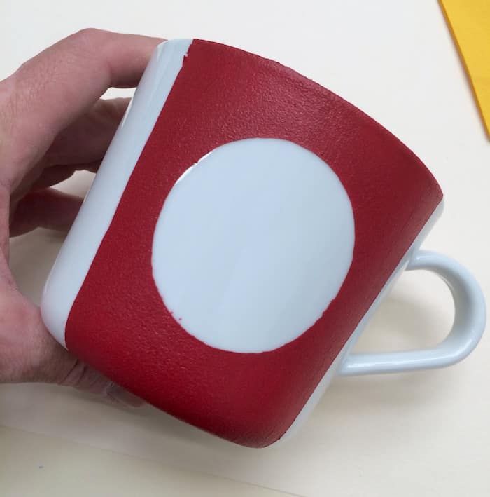 White mug painted with a red stripe on the front and circle in the middle