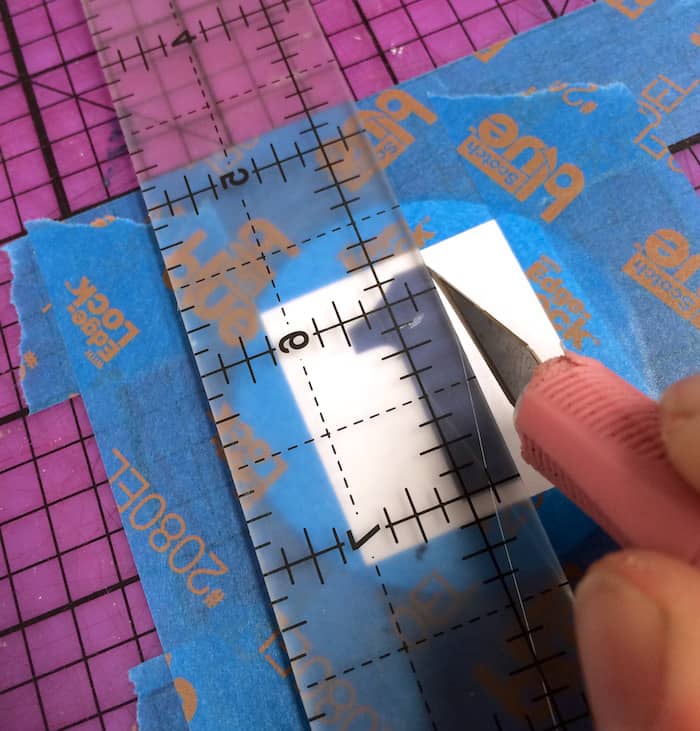 Using a craft knife and ruler to cut out a number one