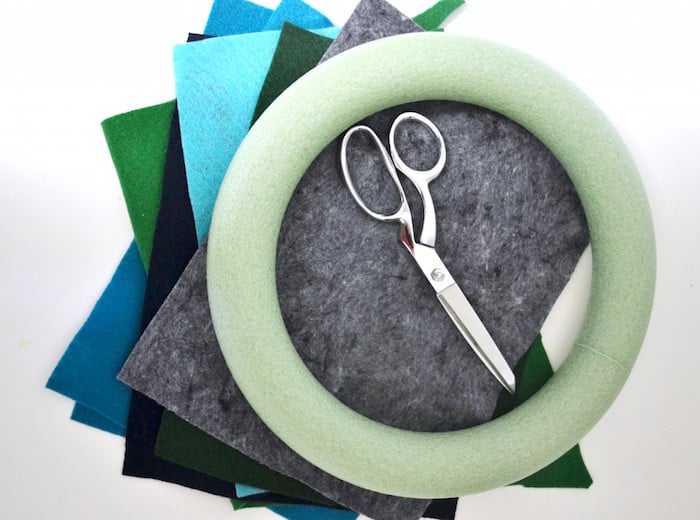 stack of felt in different colors, pair of scissors, and a green foam wreath form