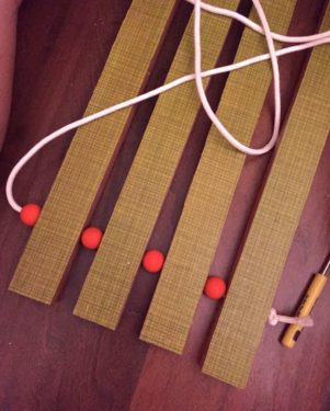 Stringing the wood doormat with beads and rope