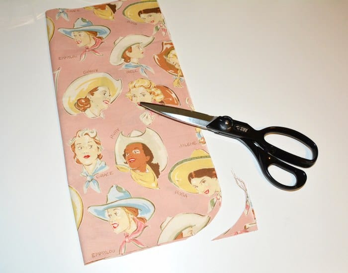 Rounding the bottom edge of a piece of fabric with a pair of scissors