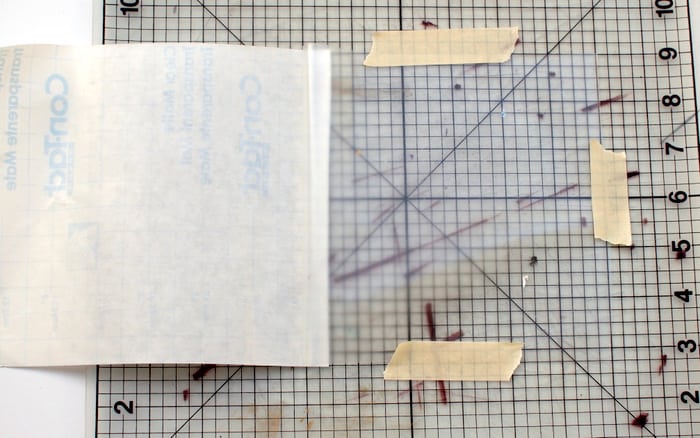 Cutting a piece of clear contact paper on a cutting mat