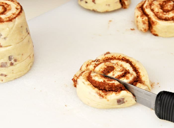 Using a knife to cut up the cinnamon rolls