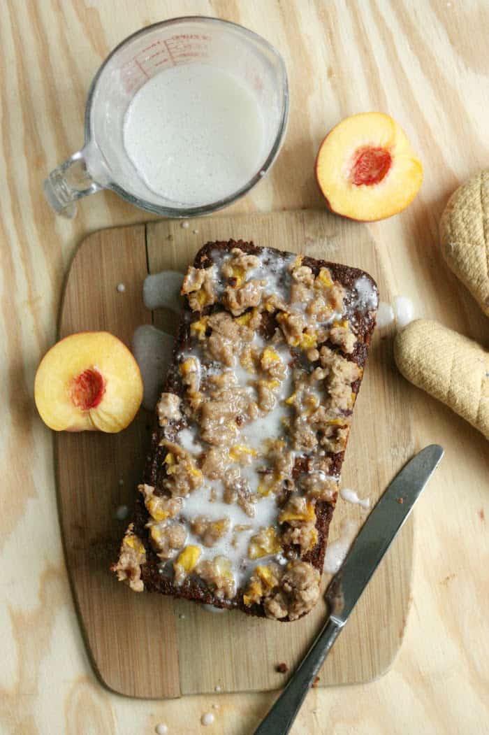 Loaf of peach cobbler bread on a cutting board with a knife laying next to it