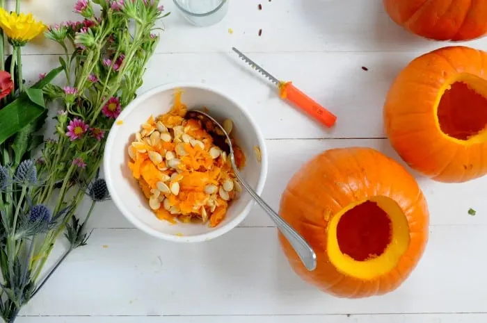 Bowl filled with pumpkin guts and seeds with a spoon in it