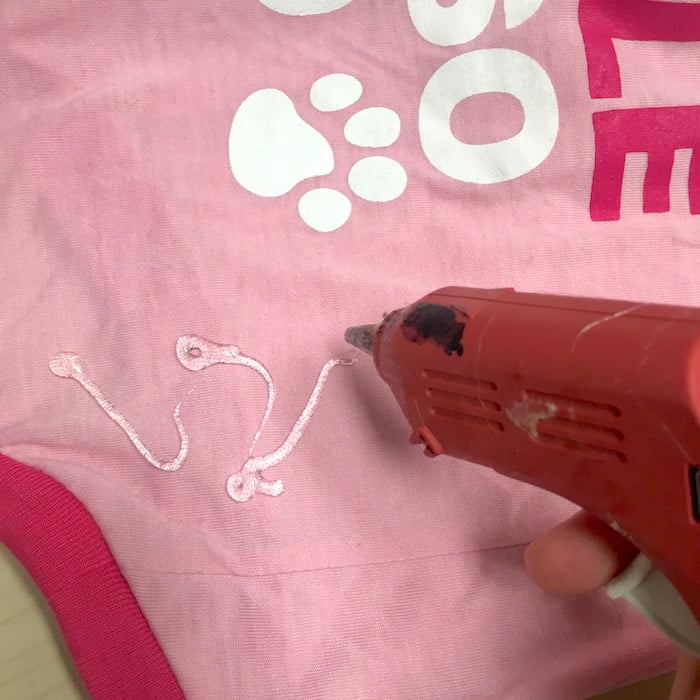 Adding hot glue to a dog t-shirt with a hot glue gun