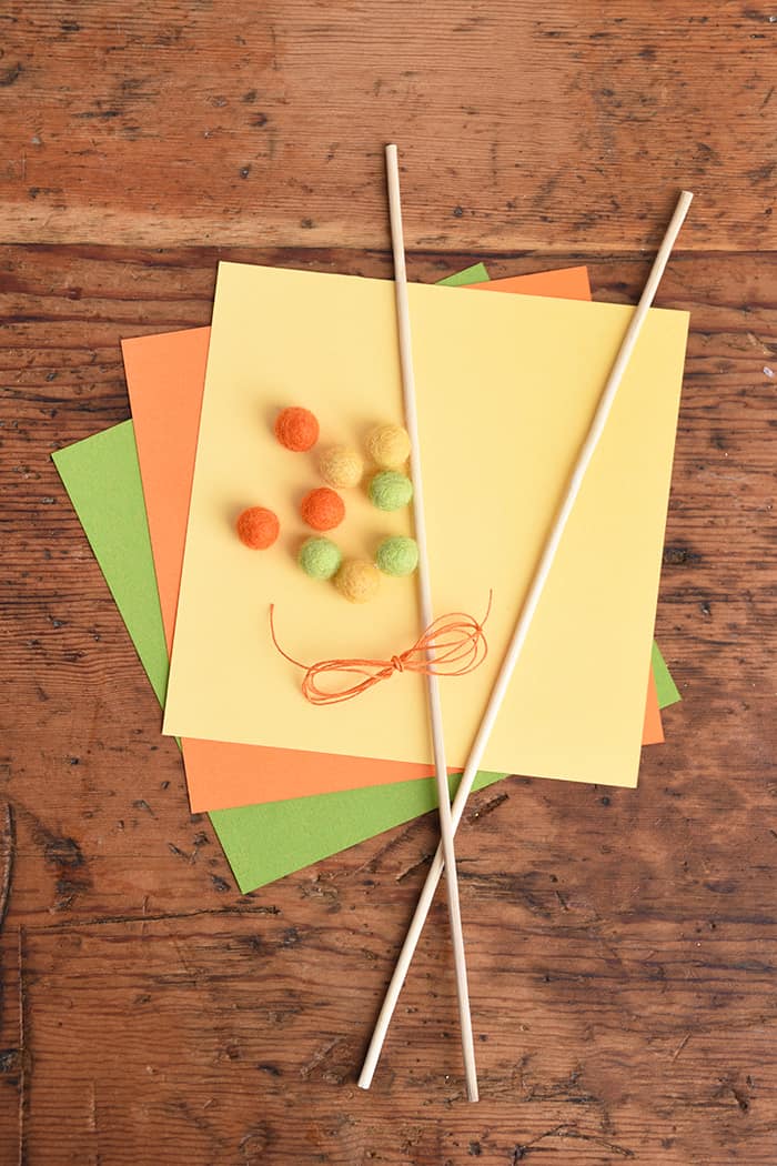 Cardstock in yellow, orange, and green with felt balls, string, and dowels