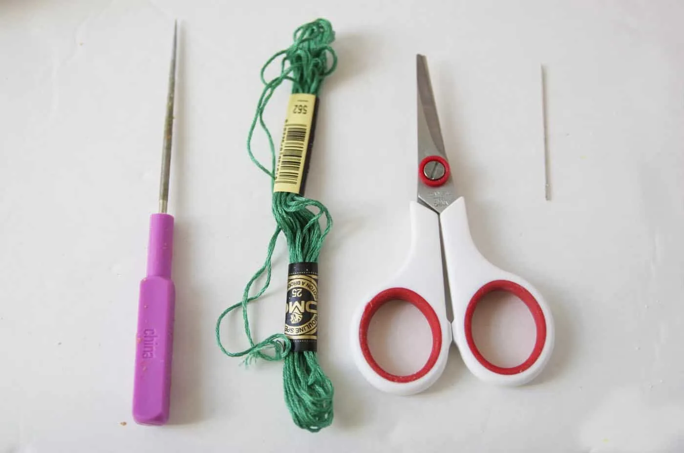Awl, embroidery thread, scissors, and a needle