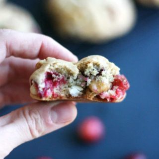 hand holding a cranberry white chocolate cookie with a bite in it