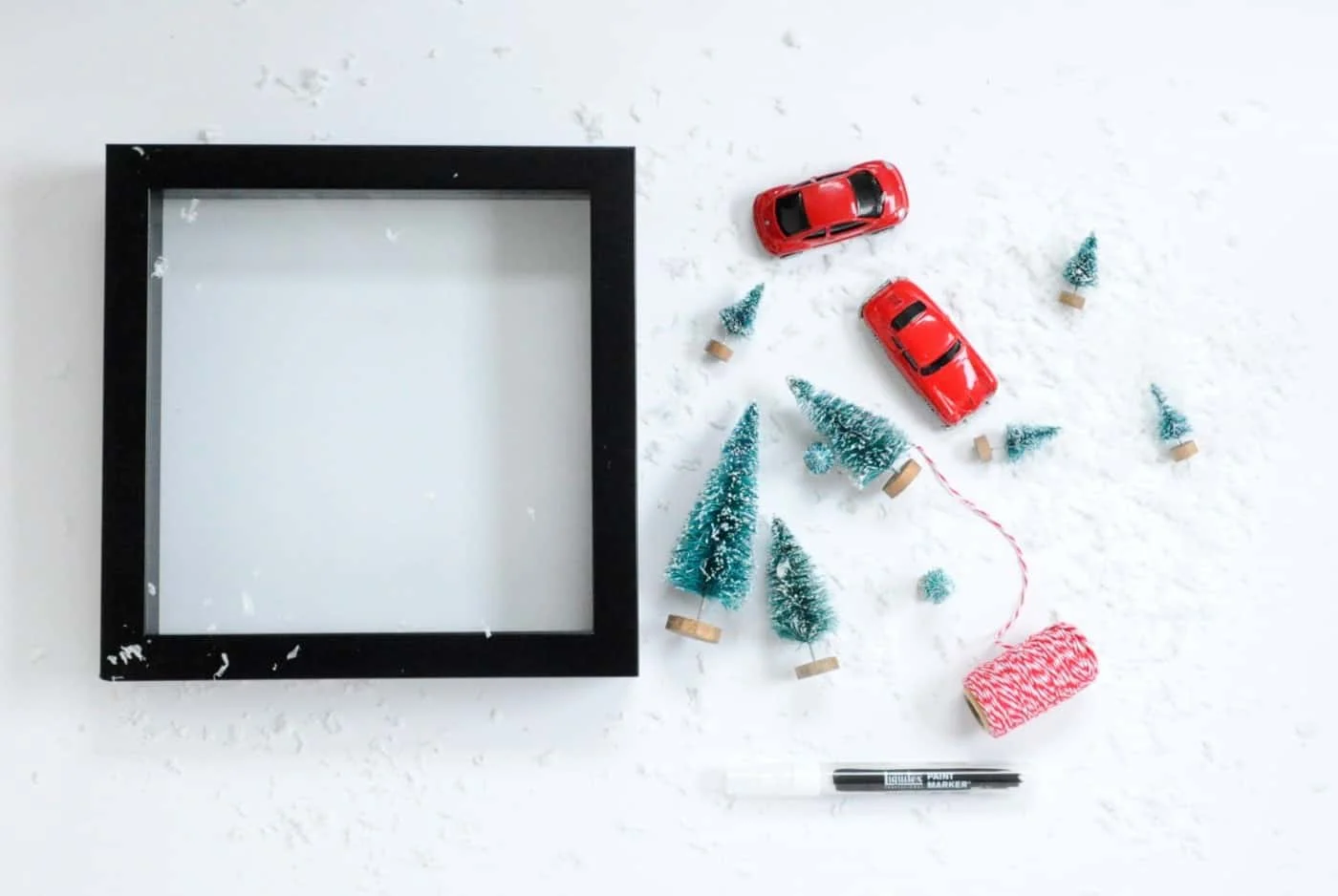 Black shadow box, two red cars, and mini brush tress