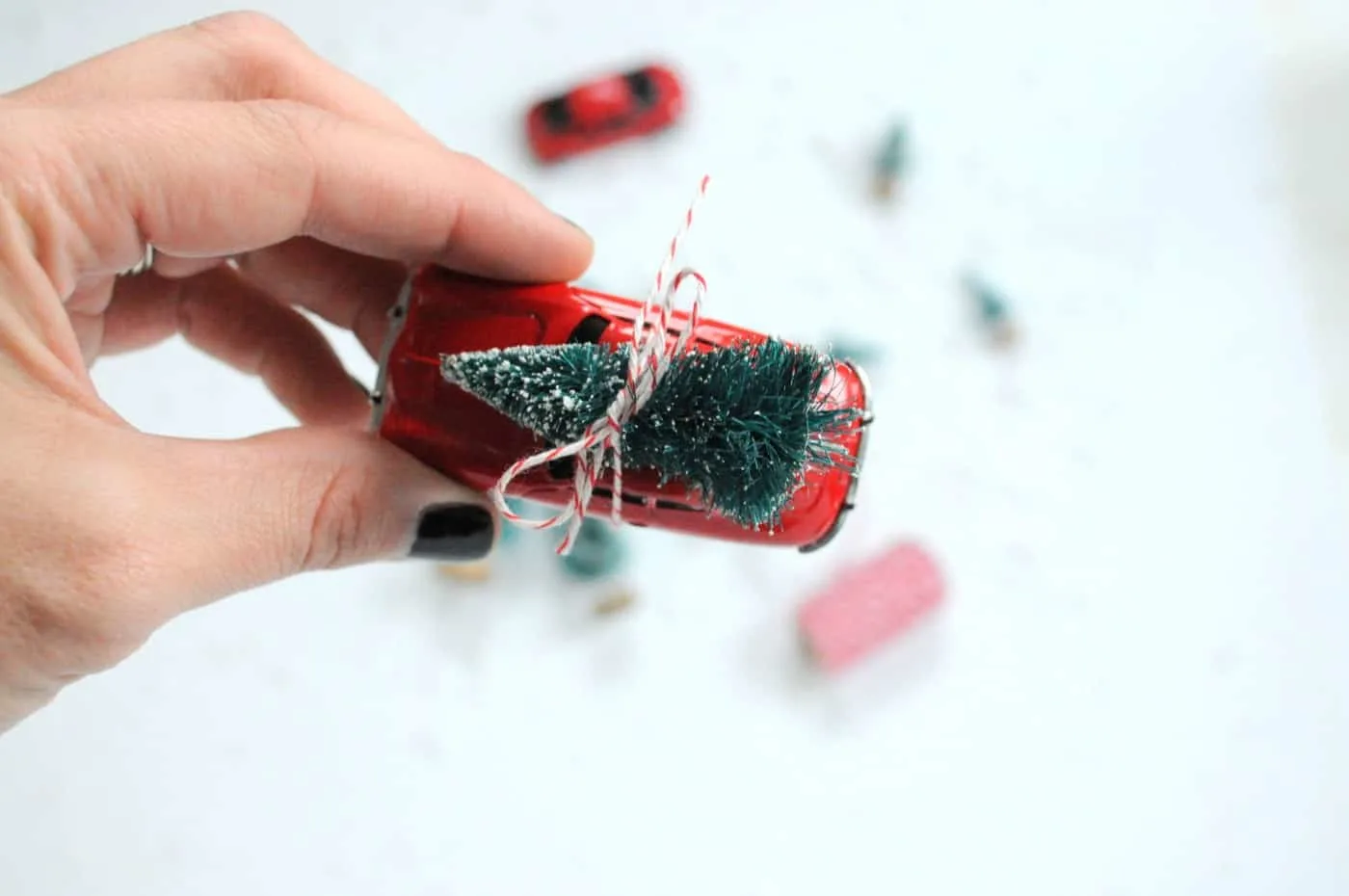 Tie a bottle brush tree to the top of a red car