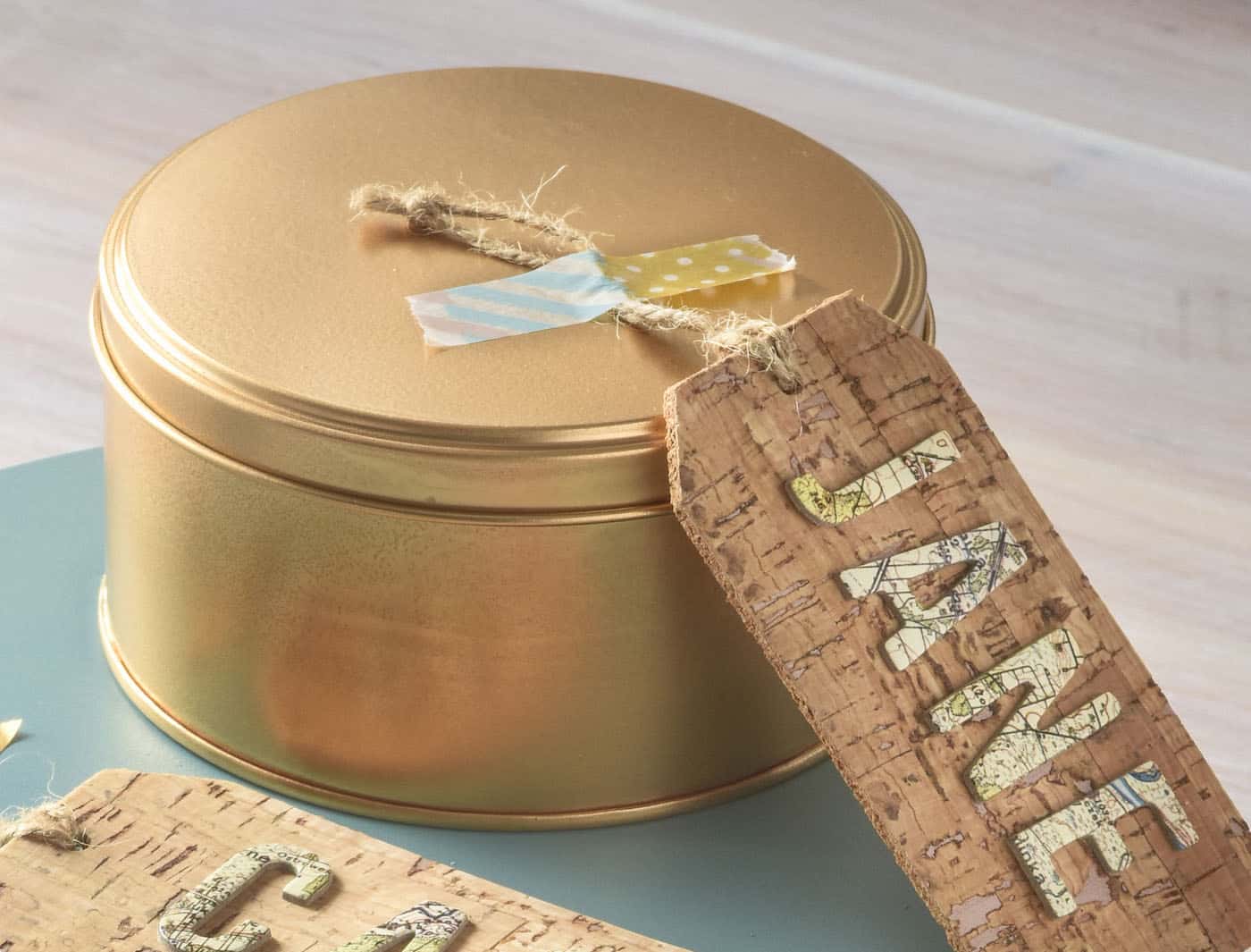 Gold spray painted cookie tin with a cork tag that says "Jane"