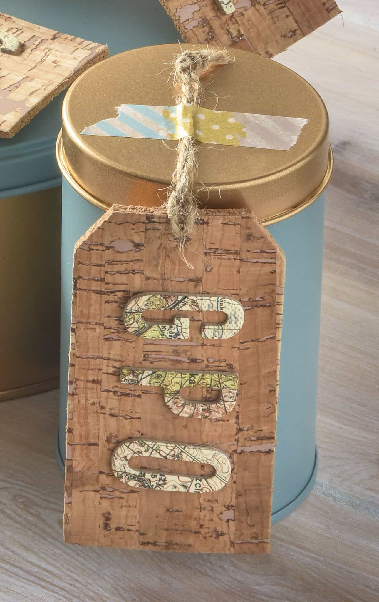 Small spray painted metal cookie tin with a cork tag