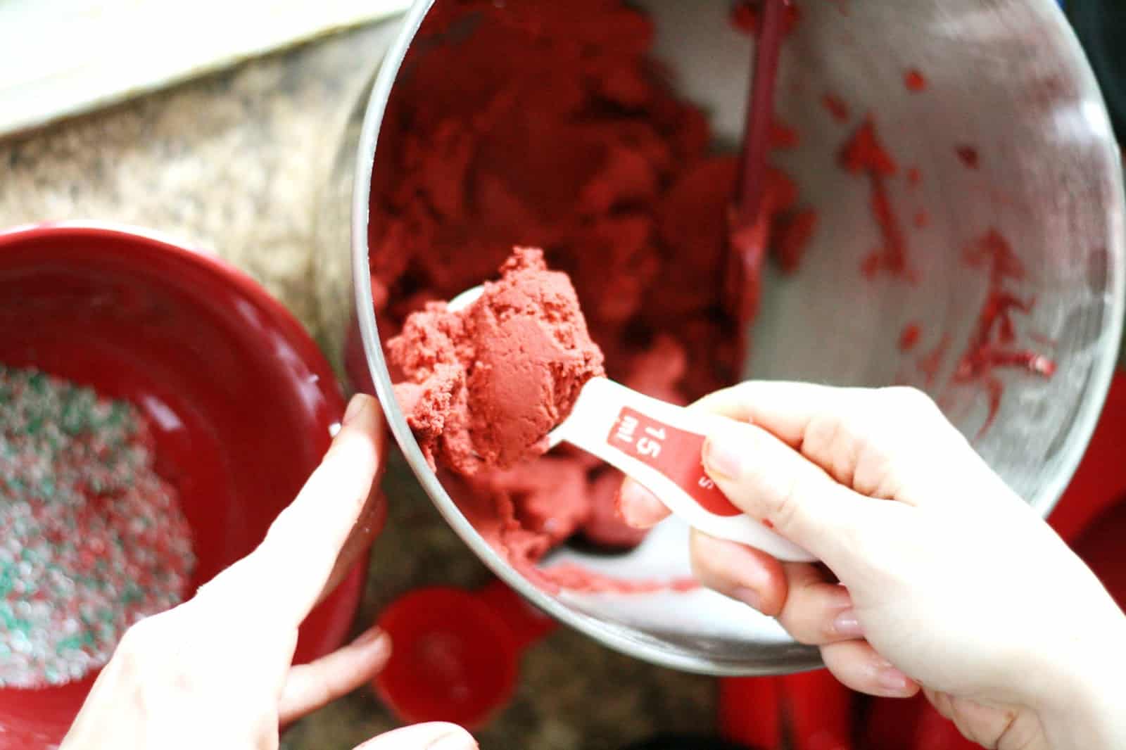 Scooping red velvet cookie dough from a bowl