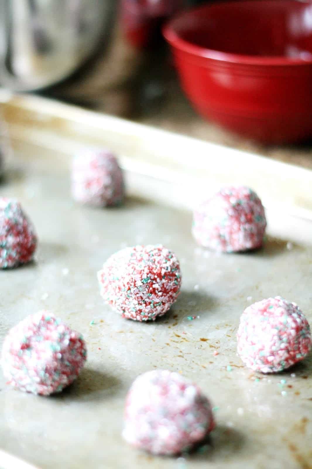 Red velvet cookie dough balls on a cookie sheet
