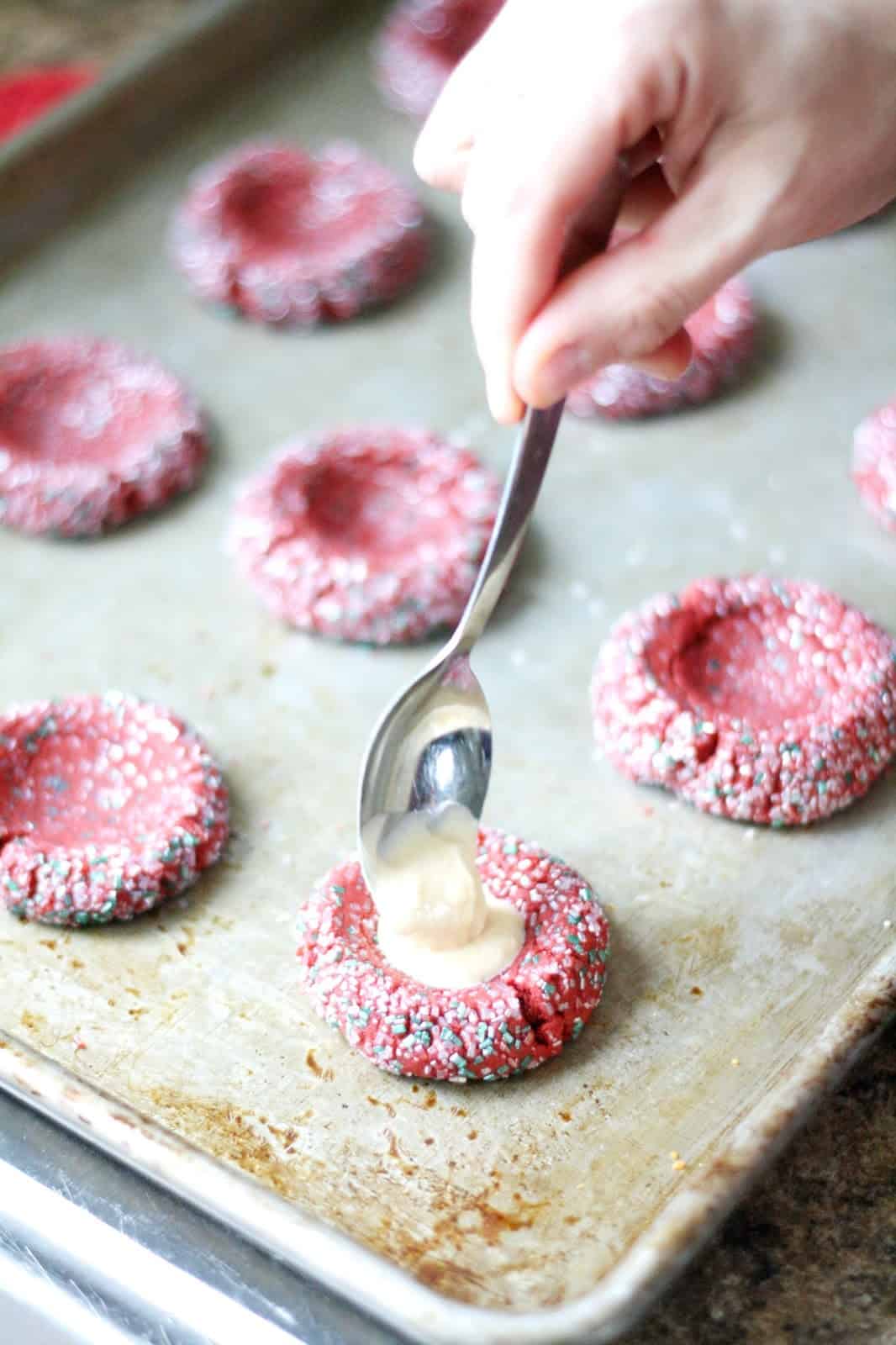 Adding cream cheese filling to the cookies with a spoon