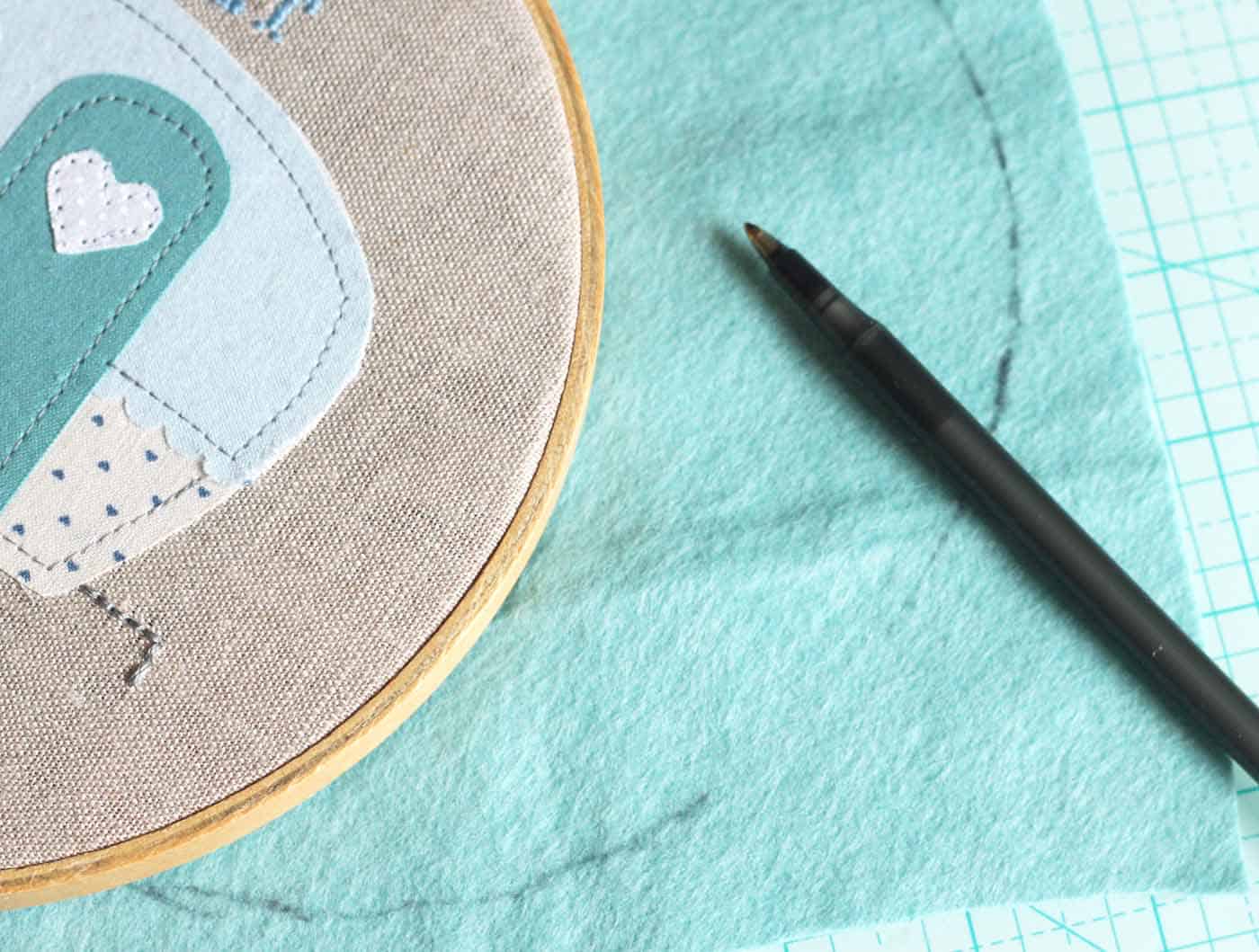 Tracing a circle of blue felt with an embroidery hoop