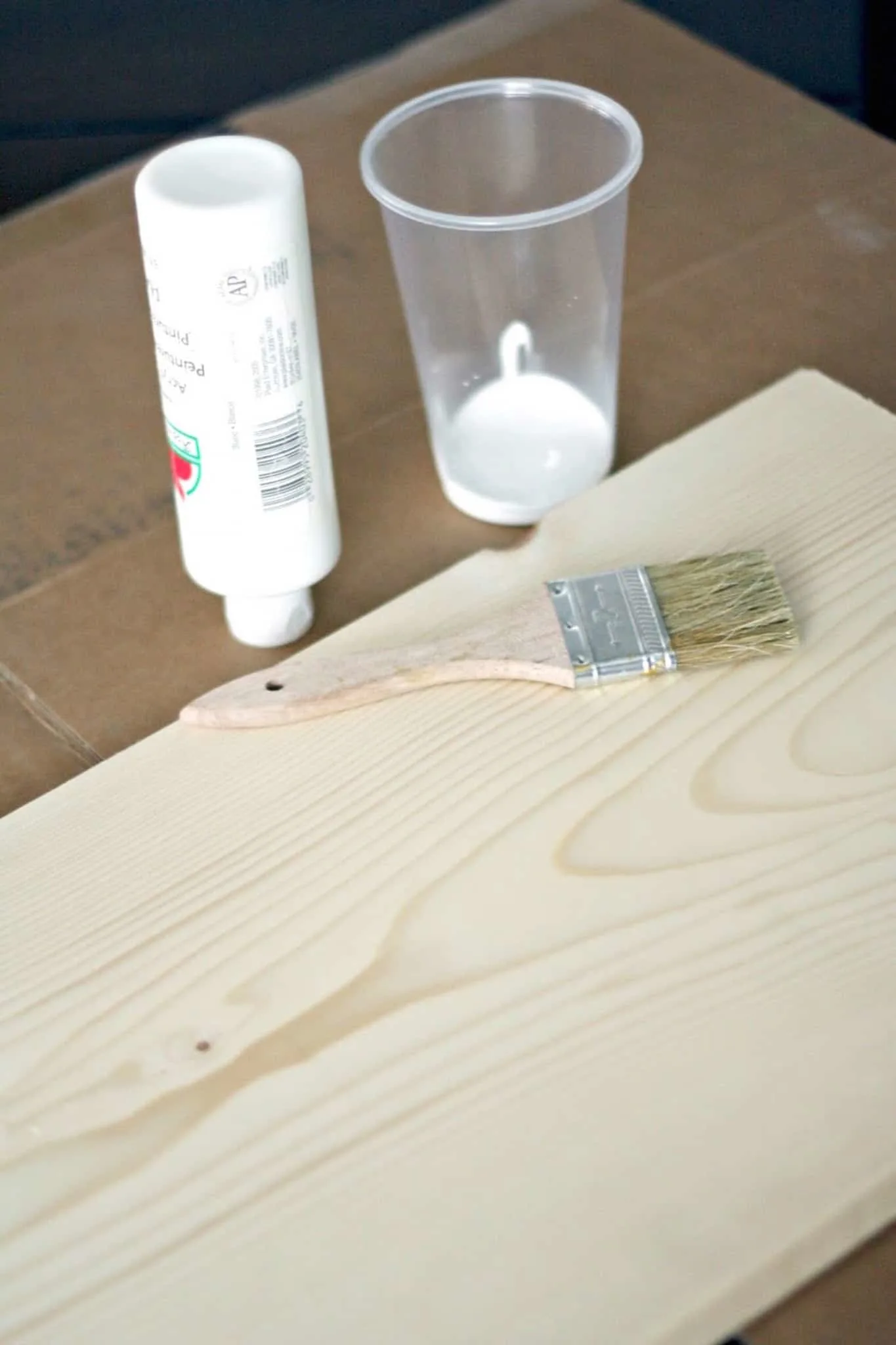 White craft paint, piece of wood, and a paintbrush