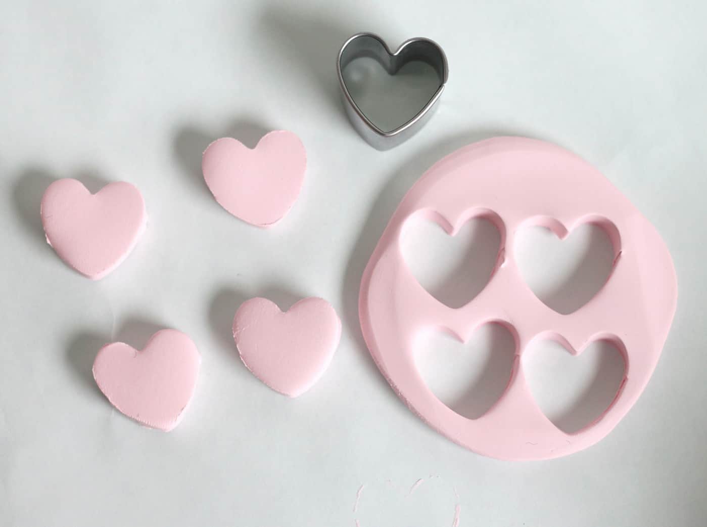 Cutting hearts out of pink polymer clay with a heart cookie cutter