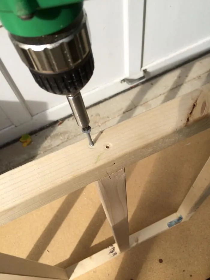 Using a drill to attach the cross pieces to the wood frames