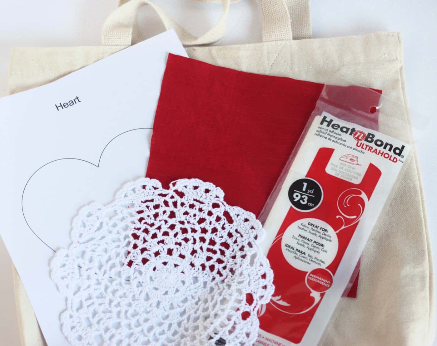 Canvas tote bag, heart template, white doily, red fabric, and Heat n' Bond Ultrahold
