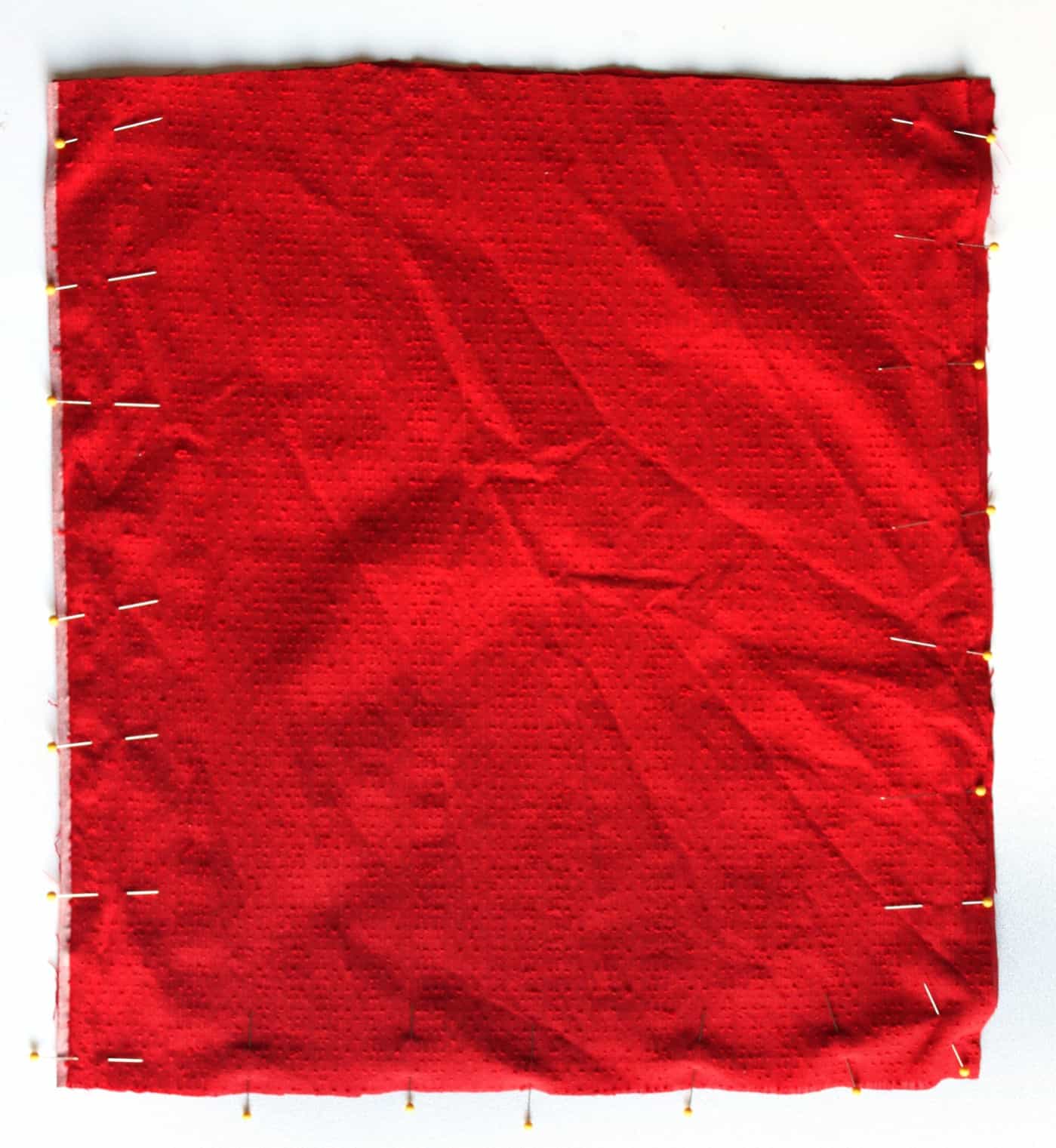 Red fabric lining pinned together on a work surface