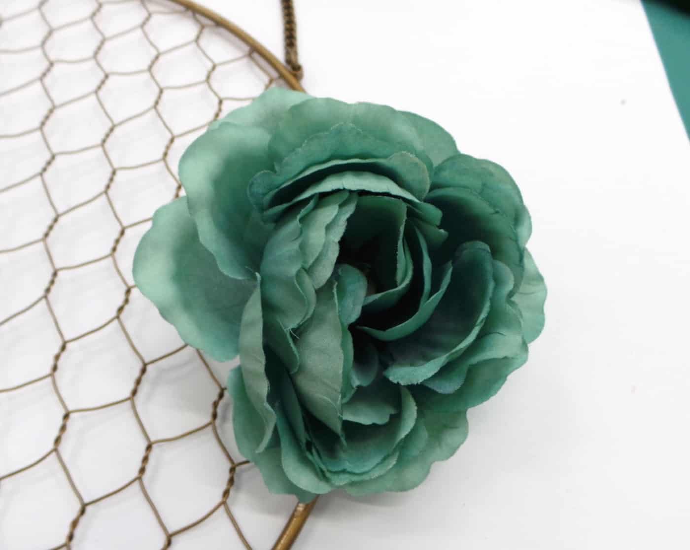 Blue green faux flower attached to a metal frame