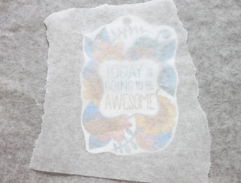 Shrinky Dink on the baking sheet and covered in parchment paper