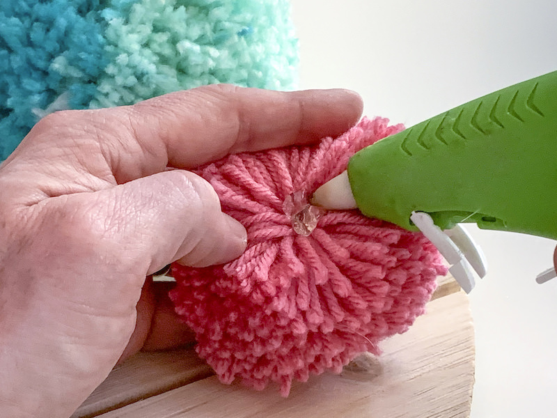 Applying hot glue to a pom pom
