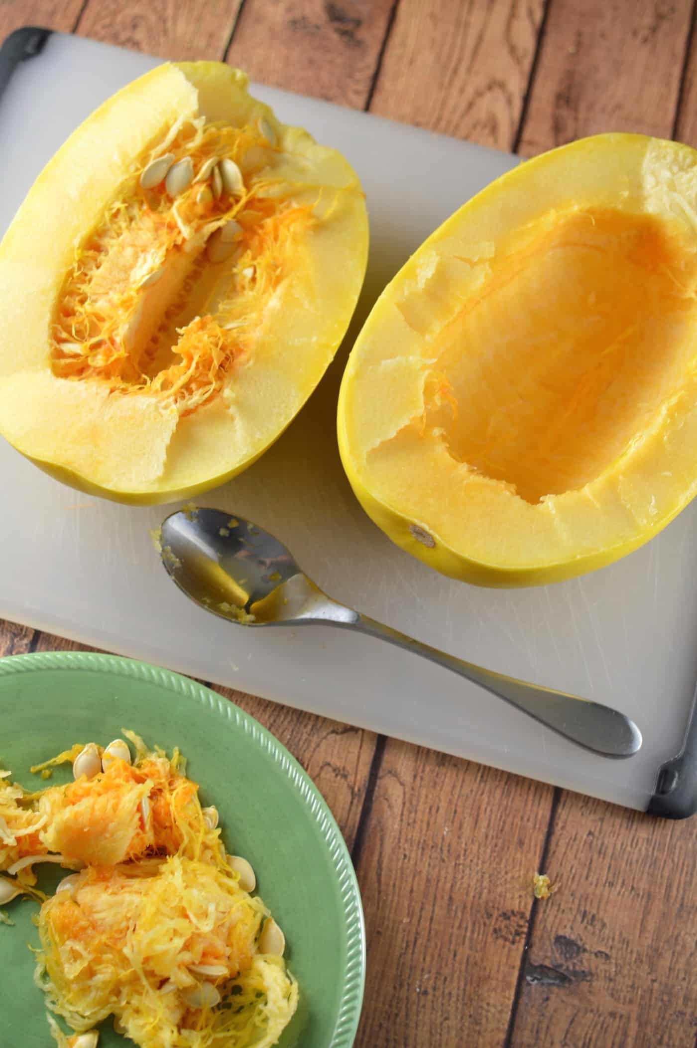 Scooping the guts and seeds out of a spaghetti squash with a spoon